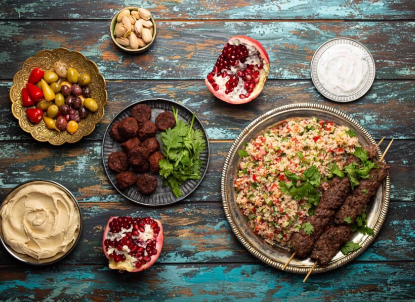 Various Turkish dishes: meat kebab with tabbouleh salad, falafel, hummus, olives, pistachios and other Middle Eastern meze on wooden table top view. Ethnic arab food, cuisine of Turkey
